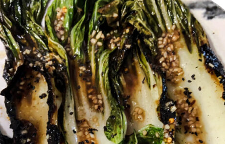 Grilled bok choy drizzled with sesame garlic dressing and sprinkled with sesame seeds.