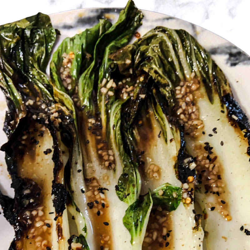 Grilled bok choy drizzled with sesame garlic dressing and sprinkled with sesame seeds.