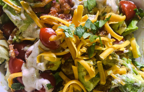 Cajun Chicken Cobb Salad with iceberg lettuce, avocado, bacon, cherry tomatoes, and cheddar cheese, topped with Cajun Ranch dressing.