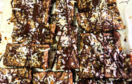 Date and coconut bars topped with melted dark chocolate and toasted coconut flakes.