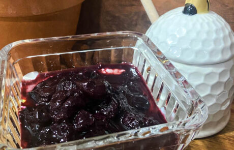 Greek yogurt served with a cherry compote in a glass dish.