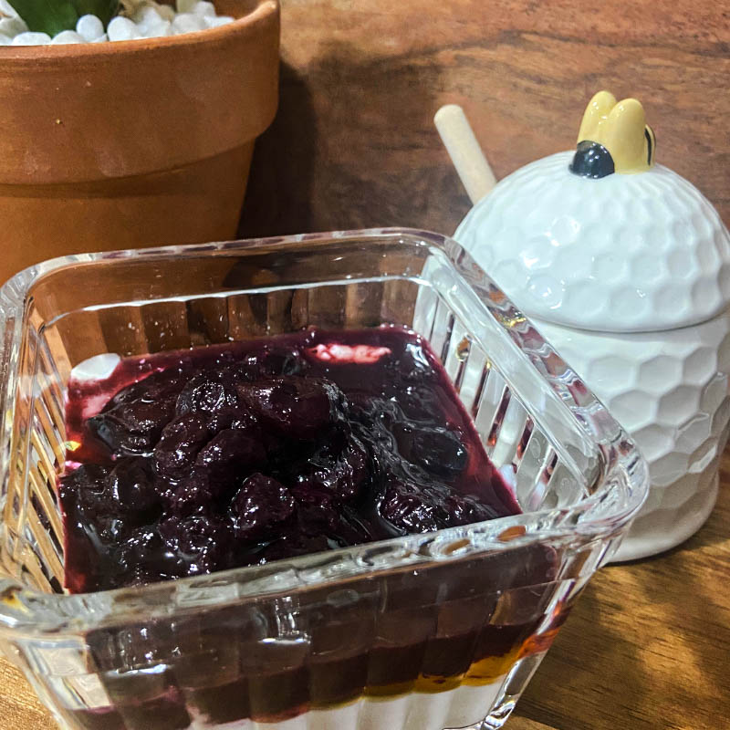 Greek yogurt served with a cherry compote in a glass dish.